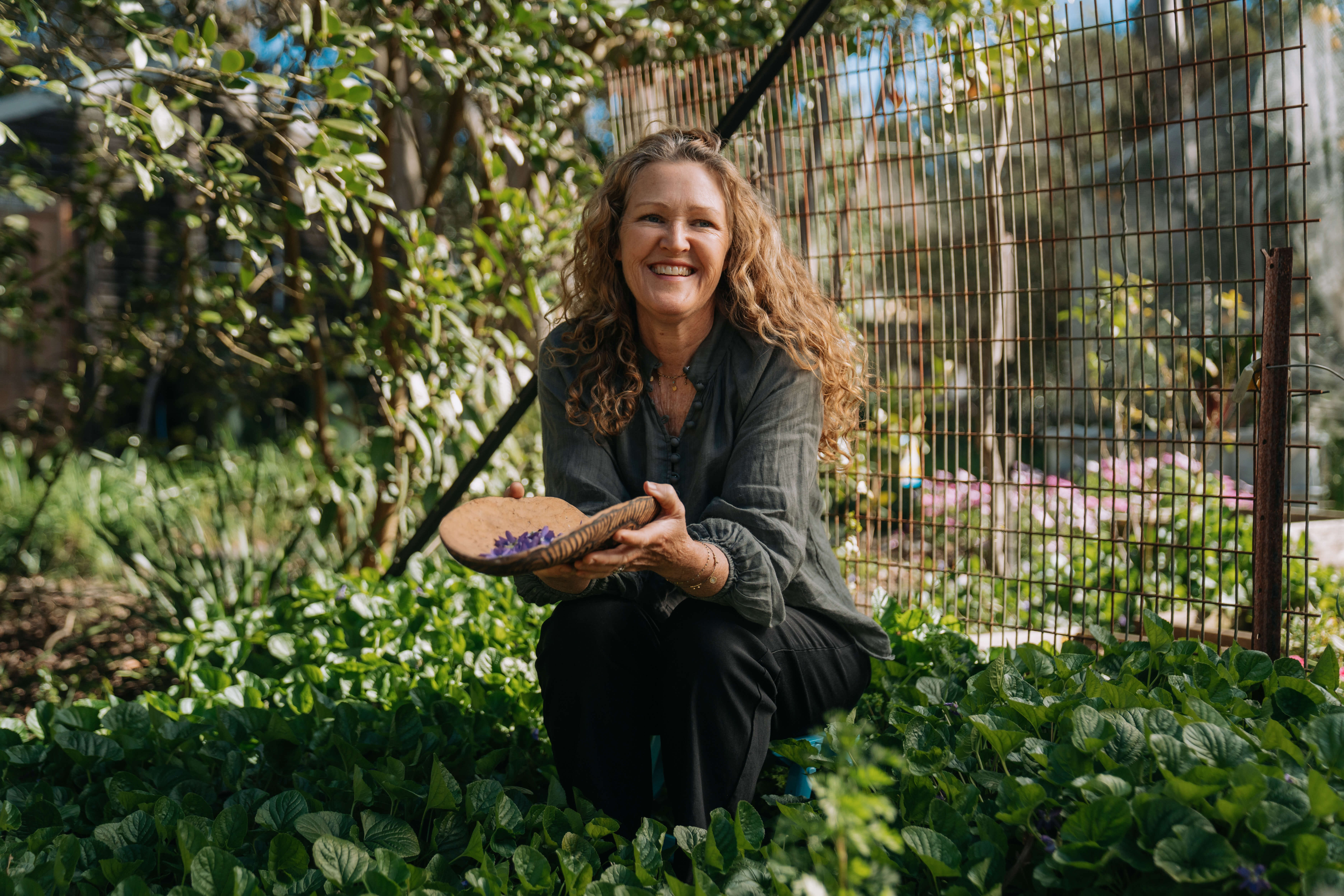 A lady sitting amongst a garden and smiling
