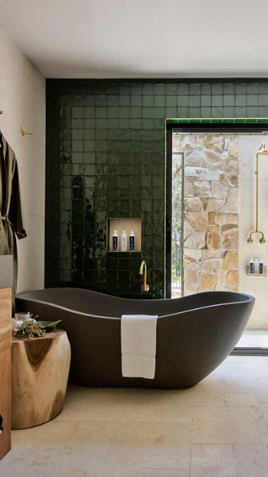 A concrete bathtub sitting in front of a large green tiled wall