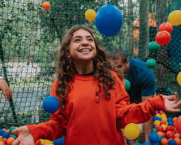A child looking excited as they play in a colourful ball pit