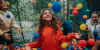 A child looking excited as they play in a colourful ball pit