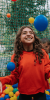 A child looking excited as they play in a colourful ball pit